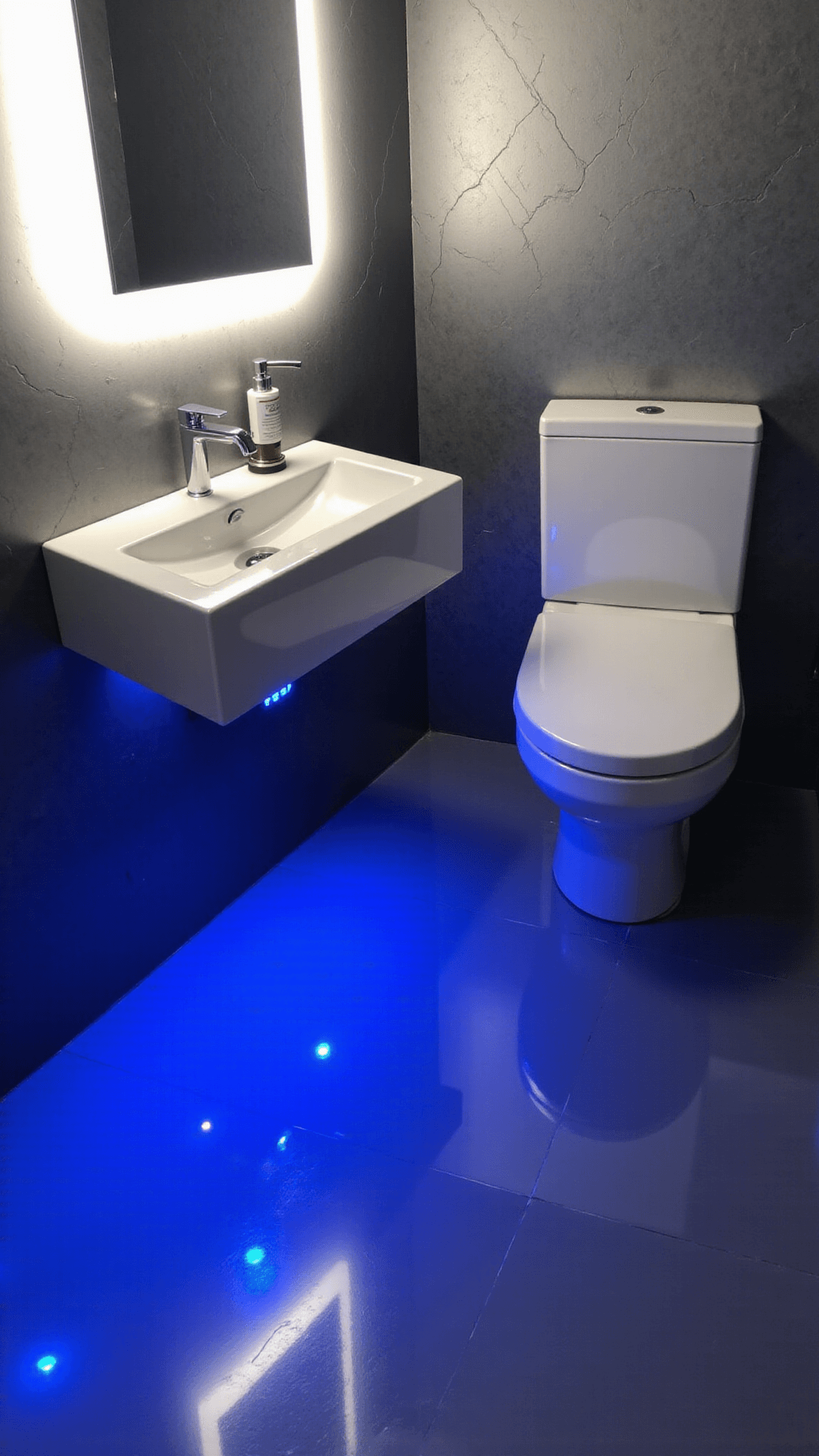Above view of an ultra-modern 8x10ft powder room with temperature-responsive LED lit flooring, high-gloss white floating vanity, backlit mirror, and metallic geometric-patterned wallpaper in charcoal, white, and electric blue color scheme.