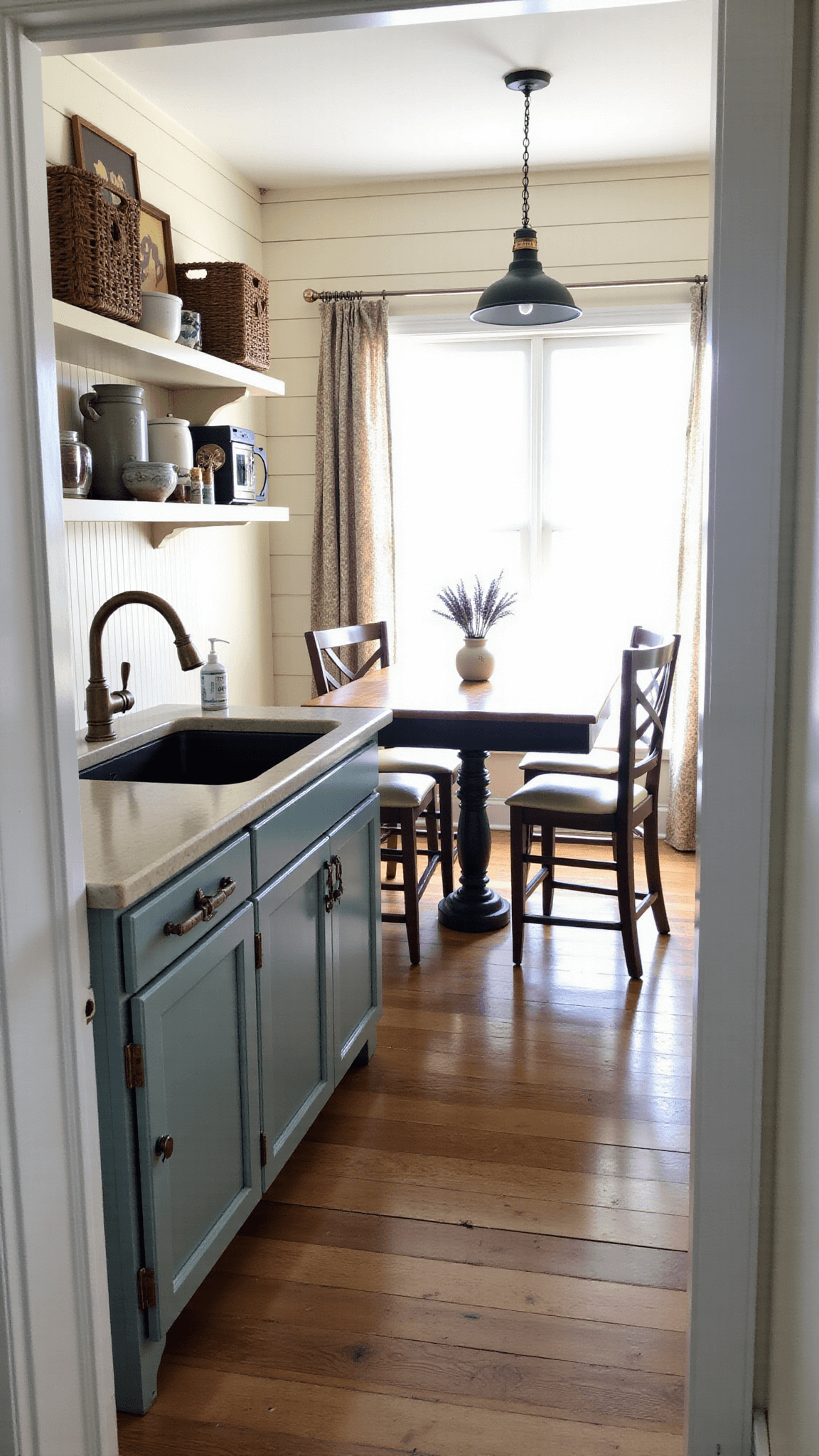 Rustic farmhouse kitchen with grayish-teal beadboard cabinets, cream shelving, vintage brass sink fixtures, oil-rubbed bronze hardware, pine dining table, industrial pendant lights, and décor of antique crockery, woven baskets, and dried lavender bunches in soft afternoon light.